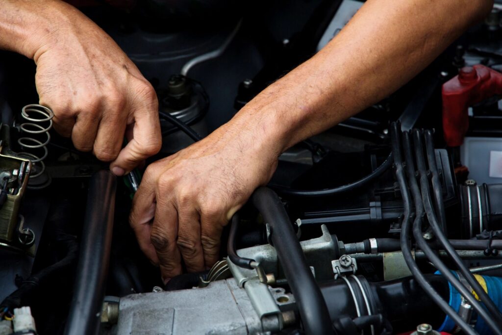 Close-up of a mechanic working on a car engine with a small tools in hand.