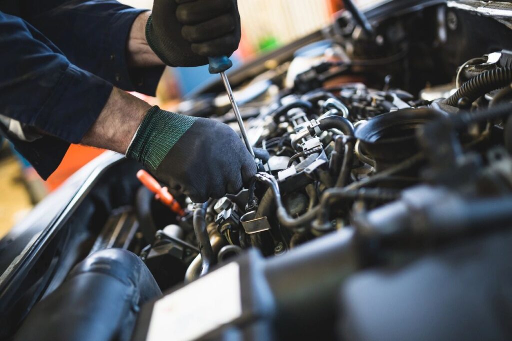 Close-up of a mechanic working on a car engine with tools in hand.